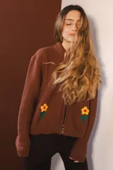 Bomber negra con rayas verticales blancas y flores rojas bordadas. Tiene cierre frontal y bolsillos.