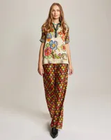 Pantalón fluido de viscosa con estampado geométrico en tonos rojo, naranja, amarillo y verde. Presenta cintura elástica y detalle de denim en los laterales.