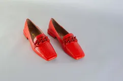 Mocasines fucsia con estampado de piel de serpiente y detalle de cadena plástica en el empeine.