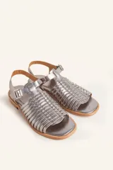 Sandalia de cuero color marrón con diseño de tiras entretejidas y hebilla lateral.