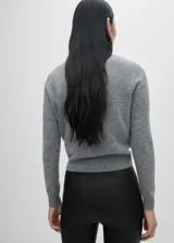 Cárdigan gris de punto fino con cuello redondo y cierre frontal con botones. Tiene costuras decorativas en negro en cuello, botones y borde frontal.