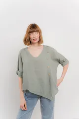 Blusa color naranja confeccionada en 100% lino, con escote en V, mangas cortas con vuelta y silueta amplia. Presenta terminación asimétrica y fila de botones decorativos en uno de los hombros.