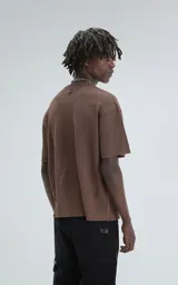 Remera de tejido de punto color café, con mangas cortas y cuello redondo. Presenta una textura calada y un calce ligeramente oversize.