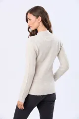 Campera tejida de abrigo color beige, con cierre frontal, cuello alto y bolsillos laterales.