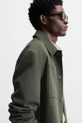 Sobrecamisa verde oscuro de corte cuadrado, con cuello solapa, manga larga con puños abotonados, bolsillos de parche en el pecho y bolsillos laterales en la cadera. Cierre frontal con botones.
