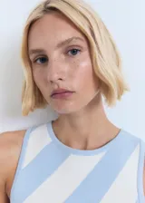 Vestido corto sin mangas, con cuello redondo y diseño a rayas diagonales celestes y blancas.