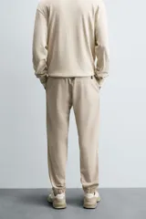 Pantalón jogger negro de corte slim fit, confeccionado en tejido de algodón con cintura elástica ajustable con cordón, bolsillos frontales y traseros de vivo, y bajo con puño elástico.