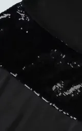 Vestido largo negro con escote halter drapeado, espalda descubierta y una banda de lentejuelas negras en la cintura.