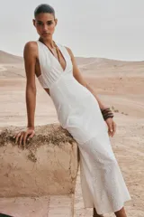 Vestido midi blanco con bordados florales perforados, escote en V, sin mangas y tirantes cruzados en la espalda.