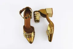 Zapato de cuero color dorado con punta fina, taco cuadrado y pulsera con hebilla y ojales.