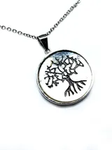 Collar con dije circular plateado con diseño calado de árbol de la vida sobre fondo de nácar.