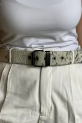 Cinturón con estampado animal print de vaca, hebilla metálica plateada y dos remaches plateados.