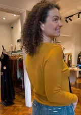 Sweater color mostaza de tejido de punto fino, con escote en V y mangas largas.