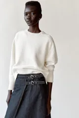 Falda midi de denim azul oscuro, de tiro alto, con diseño cruzado, abertura frontal y ajuste lateral con doble hebilla metálica.