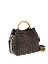 Bolso tipo cubo tejido en tonos marrón y negro, con asa superior de bambú y correa bandolera de tela con diseño geométrico.