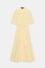 Vestido camisero midi de popelina color amarillo pálido, con cuello solapa, mangas cortas con puños abotonados, bolsillos laterales ocultos y bolsillos de parche con solapa en el pecho. Incluye cinturón lazada en el mismo tejido y cierre frontal con botones ocultos.