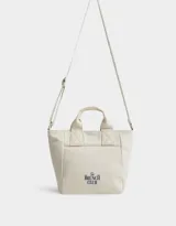Cartera mini de lona color crudo con estampado "The Brunch Club" en azul marino. Tiene correa regulable y desmontable, manijas superiores y cierre superior.