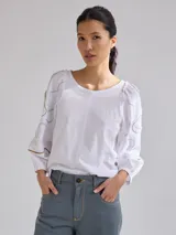 Remera gris de algodón con mangas color beige con bordados de líneas en blanco, amarillo y gris.