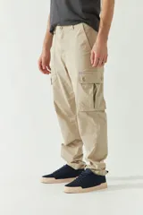 Pantalón cargo color beige para hombre, de corte recto, con bolsillos laterales y traseros. Se ajusta a la cintura con cinturón de cuero marrón.