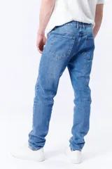 Pantalón jean de corte slim color azul medio, con bolsillos delanteros y traseros.