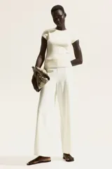 Pantalón de tiro alto color blanco, con elástico oculto en la cintura y piernas amplias con costura pespunteada doble adelante.