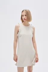 Vestido corto color crema, sin mangas, con cuello redondo y volados en los hombros.