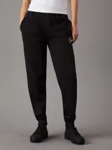 Pantalón de chándal negro de felpa con corte holgado, cintura elástica con cordón, puños de canalé, bolsillos laterales y monograma bordado de Calvin Klein en la cadera.