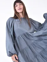 Vestido corto negro con mangas globo abullonadas y cuello redondo. El cuerpo del vestido es ajustado y la falda tiene un corte en capas con volados.