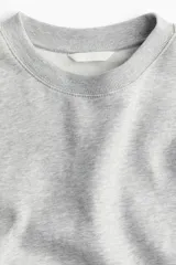 Buzo gris de corte amplio, con cuello redondo y mangas largas.