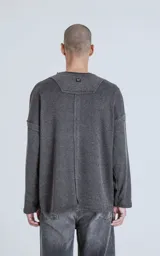 Sweater gris oscuro de corte recto, cuello redondo y mangas largas con detalle de costuras a los lados.