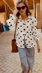 Camisa blanca con lunares negros, de corte holgado y mangas largas abullonadas con puños elásticos.