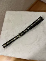 Cinto negro de cuero con hebilla metálica dorada y tachas plateadas y doradas.