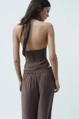 Chaleco marrón con cuello halter ajustable con lazada y escote pico. Cierre frontal con botones.