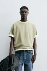 Camiseta color verde claro, de corte holgado, confeccionada en tejido de algodón con interior reversible de popelín. Tiene cuello redondo, manga corta y acabados con vivo combinado a contraste.