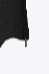 Top negro tipo corsetero con escote corazón y tirantes finos. Presenta varillas forradas que realzan la figura y cierre lateral con cremallera oculta.