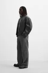 Pantalón gris oscuro de corte amplio, con bolsillos frontales y traseros de parche. Incluye un bolsillo lateral con cierre de cremallera.