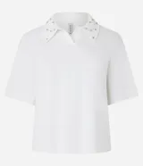 Blusa blanca de algodón con cuello polo y manga corta. Detalle de piedras aplicadas en el cuello. Corte holgado.