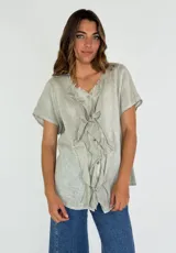 Camisa de lino y algodón color rosa claro, con cuello en V, mangas cortas y volados frontales.