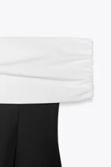 Top negro con escote recto y hombros descubiertos, con tejido combinado a contraste en blanco.