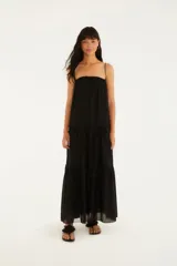 Vestido largo negro de tirantes finos y corte fluido con volantes en capas.