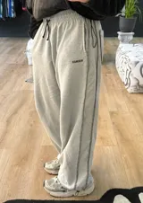 Pantalón de jogging gris con cordón ajustable en la cintura, corte holgado y puños elásticos.