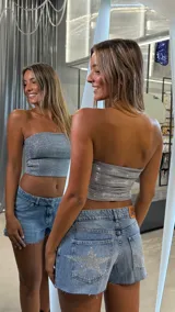 Short de jean de tiro bajo, color celeste claro, con bordes deshilachados y un gran aplique de estrella con brillos plateados en el bolsillo trasero.