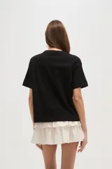 Remera negra de algodón con apliques de moños bordados en el frente, corte ancho y cuello redondo.