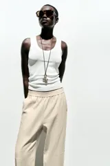 Pantalón bombacho color beige de lino, con cintura elástica, bolsillos frontales y bolsillos de parche en la espalda.