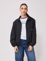 Campera negra tipo rompevientos de nylon con cierre frontal y bolsillos laterales.