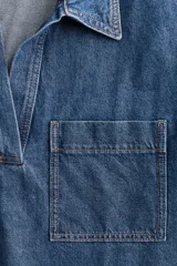 Vestido corto de denim azul, con cuello camisero, escote en V, manga corta y dos bolsillos de parche en el pecho.
