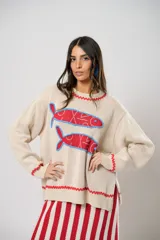 Buzo tejido color crudo con cuello redondo, puños y ruedo acanalados con detalle de galón picot rojo. Presenta dos sardinas tejidas en el frente con detalles bordados a mano en rojo y azul.