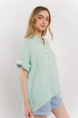 Blusa blanca de lino con escote en V abotonado y mangas cortas arremangadas.