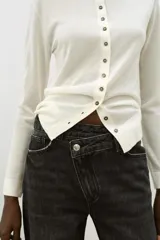 Jeans de tiro alto color negro lavado, con cintura cruzada, cinco bolsillos y pernera recta. El bajo está acabado en vuelta y tiene cierre frontal cruzado con cremallera y botones.