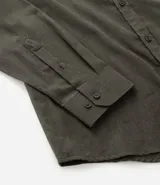 Camisa de manga larga color blanco, confeccionada en tricolina de algodón con efecto melange. Tiene cuello inglés, abotonado delantero y puños con botones.